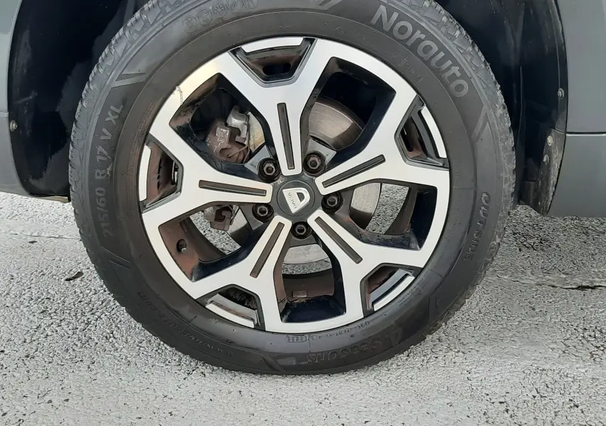 Gros plan sur la roue avant droite du Dacia Duster gris Cassiopée, mettant en valeur la jante alliage bi-ton et le pneu Norauto.