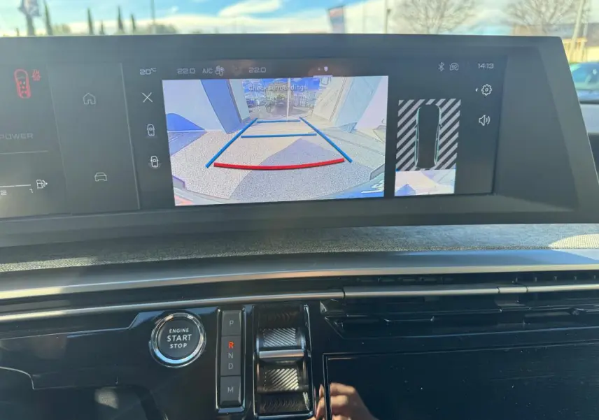 Vue rapprochée du tableau de bord du Peugeot 5008 Hybrid gris, avec écran de caméra de recul et commande de boîte auto.