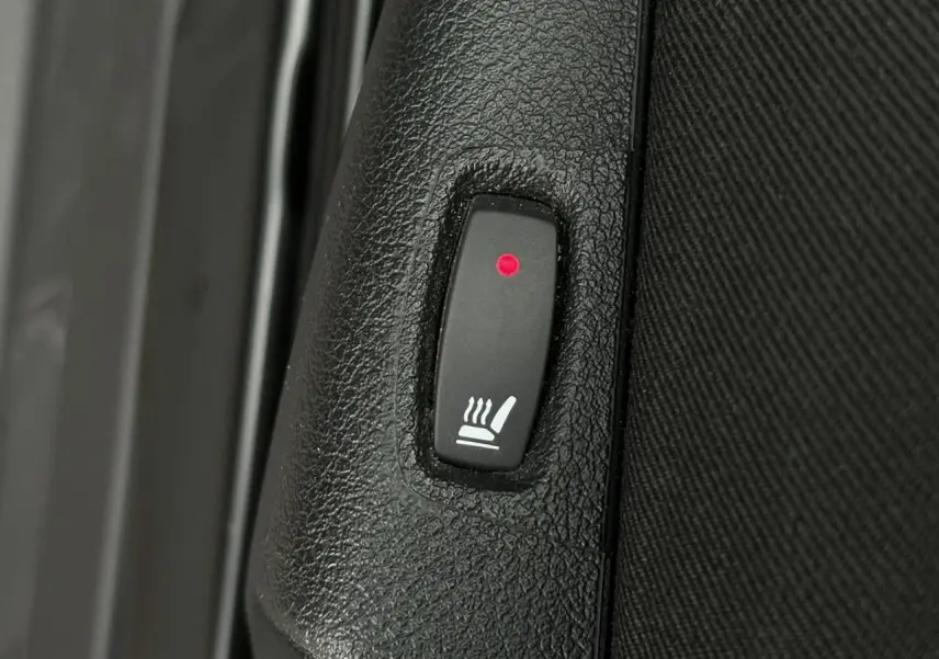Bouton de siège chauffant avec témoin rouge sur panneau intérieur noir d’un Nissan Primastar noir métal.