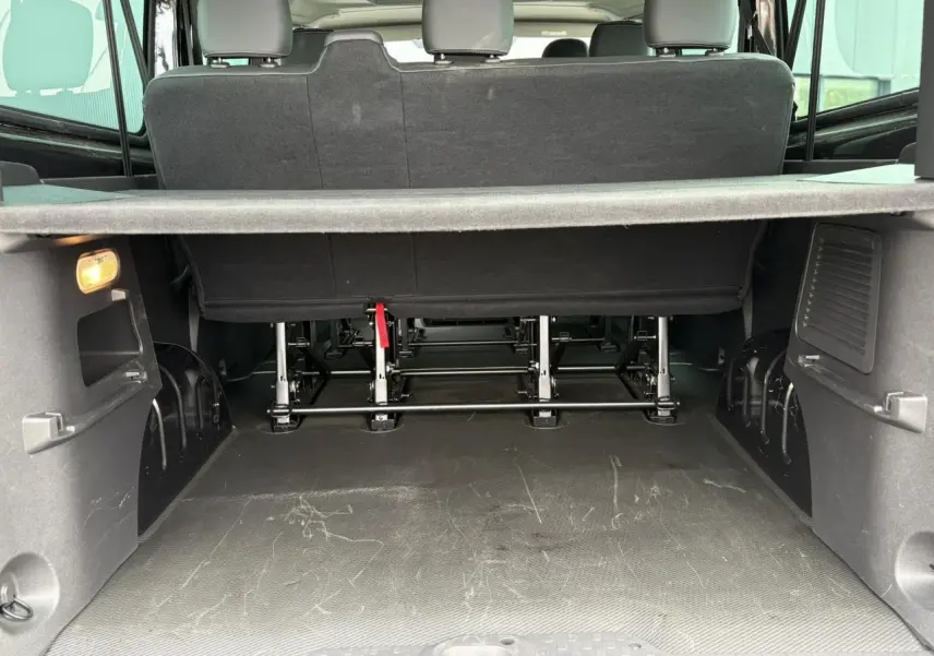 Vue arrière du coffre spacieux du Nissan Primastar noir métallisé avec banquette arrière et cache-bagages visible.