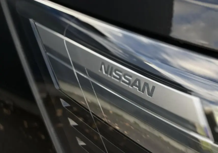 Gros plan sur la calandre noire métallisée du Nissan Primastar avec le logo Nissan en relief argenté.