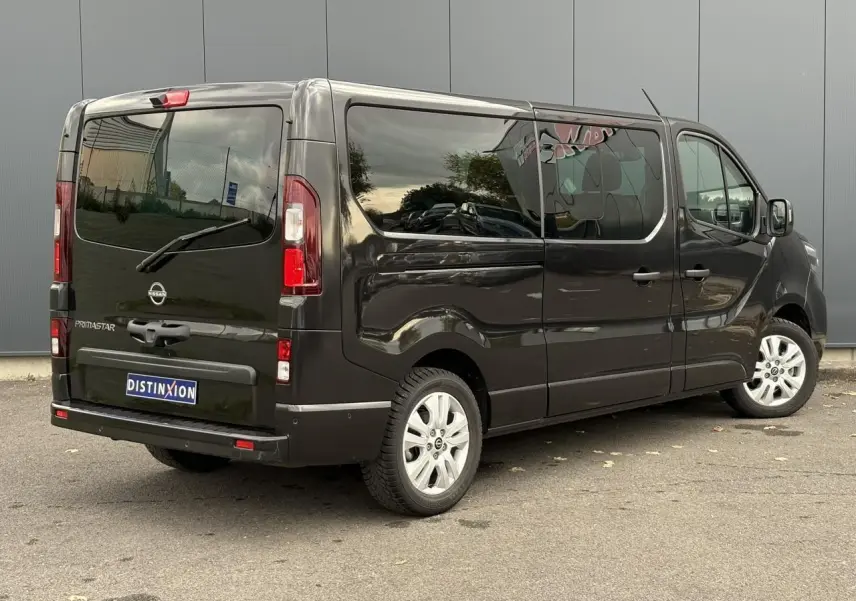 Vue 3/4 arrière droite du Nissan Primastar noir métal avec hayon vitré et vitres latérales teintées.