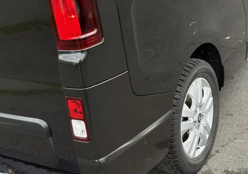 Gros plan sur l'arrière droit noir métallisé du Nissan Primastar 2025, avec feu arrière et jante alliage 17 pouces.