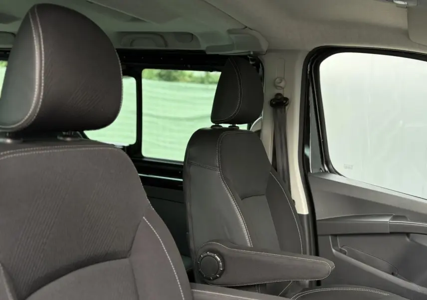 Vue intérieure côté droit du Nissan Primastar 2025 noir métallisé, mettant en valeur les sièges avant avec accoudoirs.