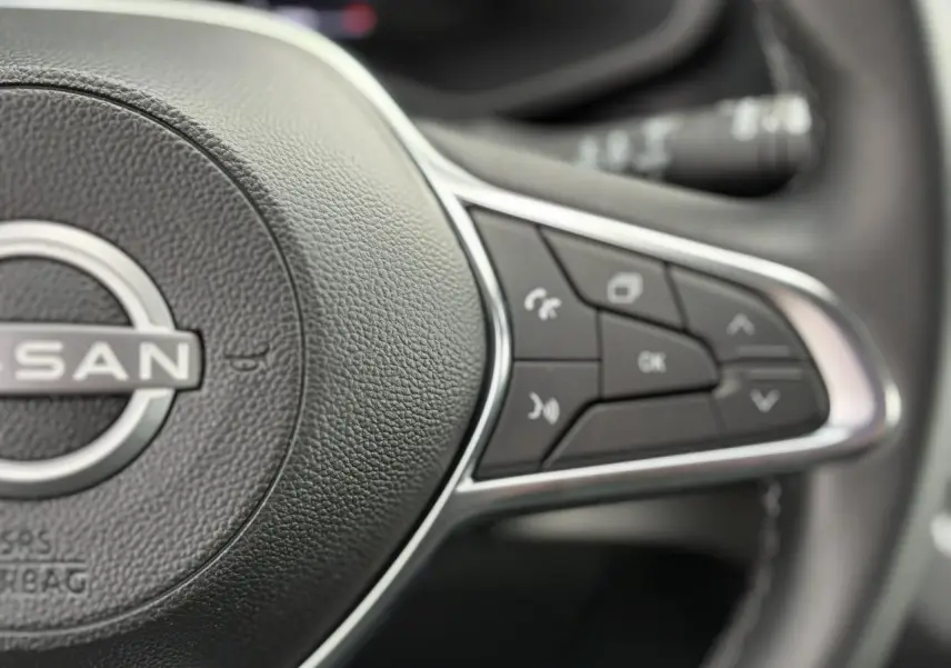 Gros plan sur le volant noir du Nissan Primastar 2025, mettant en valeur les commandes multifonctions à droite.
