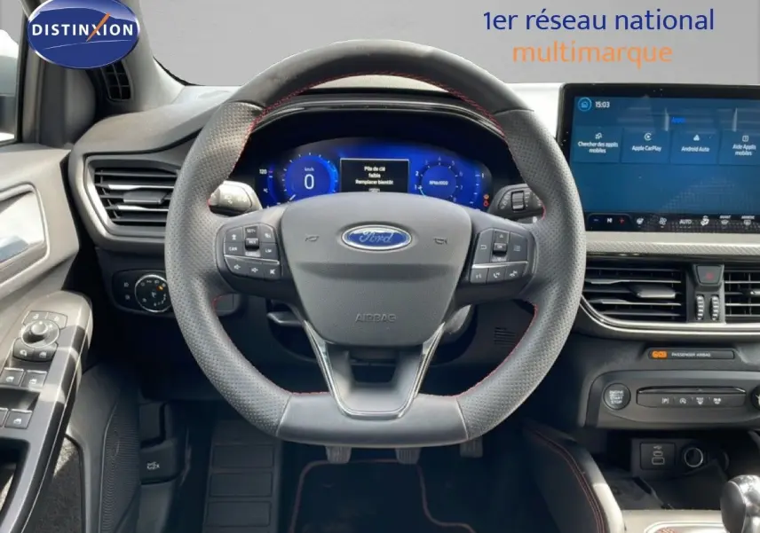 Vue intérieure centrée sur le volant perforé et l'écran tactile du tableau de bord de la Ford Focus SW gris lunaire.
