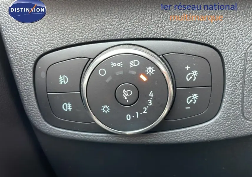 Gros plan sur la molette de réglage des phares du Ford Focus SW gris lunaire, avec commandes d’éclairage et régulateur de luminosité.