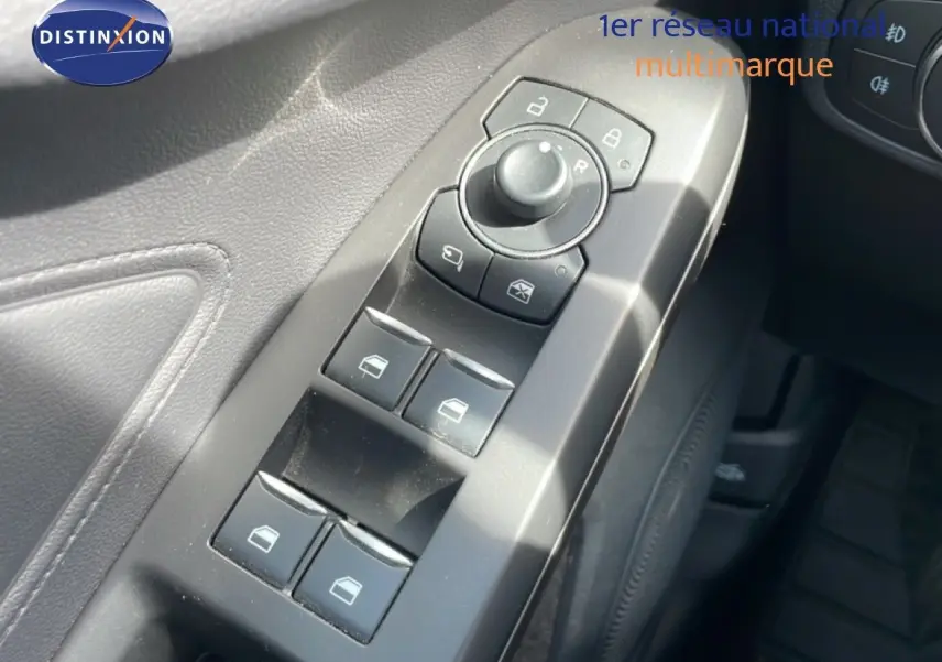 Gros plan sur les commandes de lève-vitres et rétroviseurs côté conducteur d’une Ford Focus SW 2023, intérieur noir.