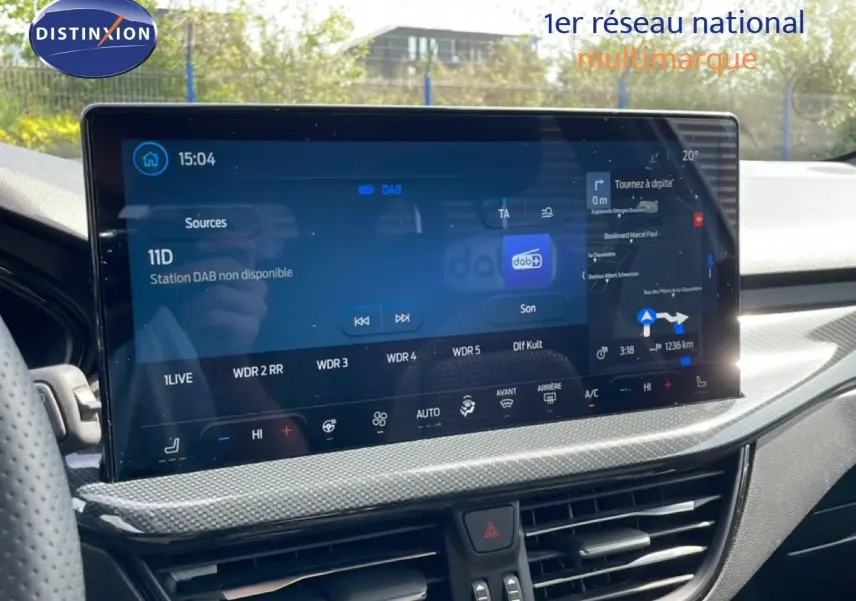 Vue rapprochée de l’écran tactile central de la Ford Focus SW 2023 gris lunaire, affichant la navigation et la radio numérique.