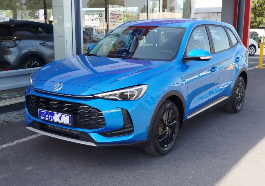 Vue 3/4 avant du MG ZS 2026 en bleu Cosmo, avec calandre noire et jantes noires, stationné devant une vitrine.