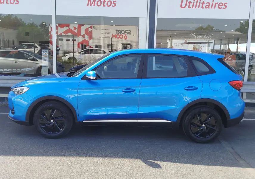 Vue de profil côté gauche d'un MG ZS 1.5 L Hybrid+ 2026 en bleu Cosmo avec jantes noires et détails noirs contrastants.