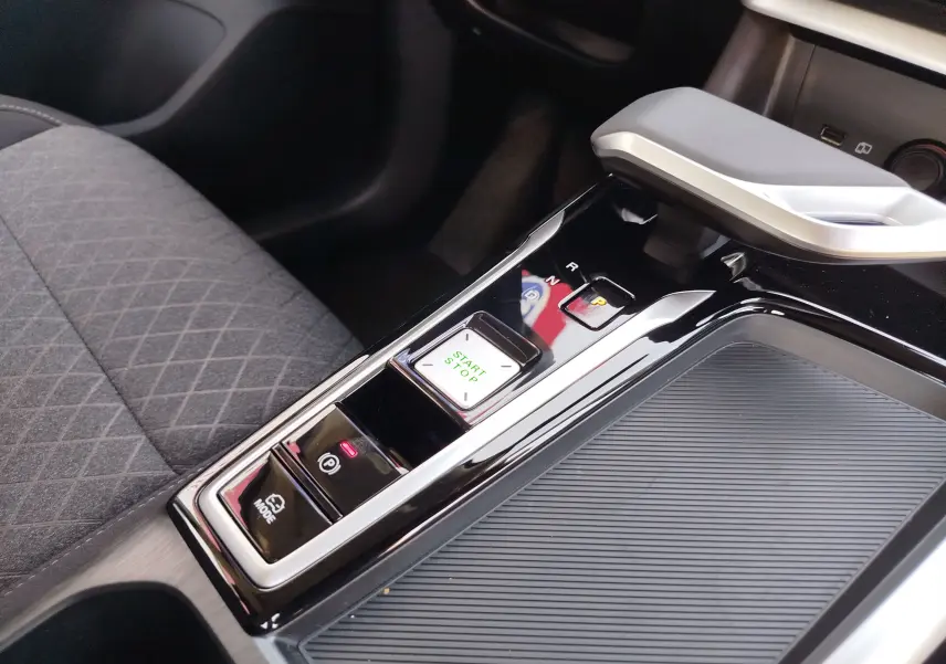Gros plan sur la console centrale noire brillante du MG ZS 1.5 L Hybrid+ avec levier de vitesse automatique et bouton start/stop.