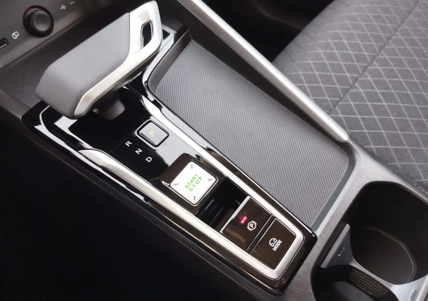 Gros plan sur la console centrale noire brillante du MG ZS 1.5 L Hybrid+ 2026, avec levier de vitesse automatique et bouton start/stop.