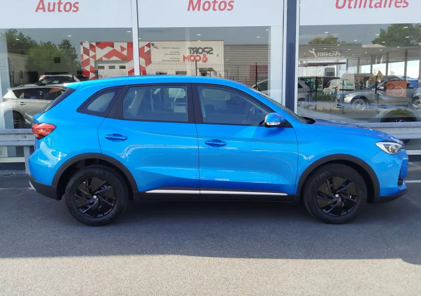 Profil droit du SUV MG ZS 1.5 L Hybrid+ 2026 en bleu Cosmo avec jantes noires et détails noirs contrastants.