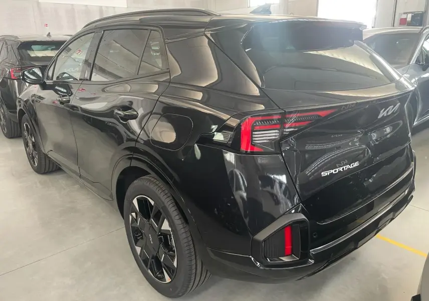 Vue 3/4 arrière droite du KIA Sportage hybride noir 2026 avec feux arrière LED et jantes noires distinctives GT-Line.