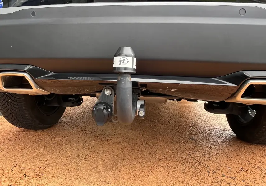 Gros plan sur l'attelage arrière du Peugeot 2008 noir 2024, mettant en valeur la prise électrique et le pare-chocs.