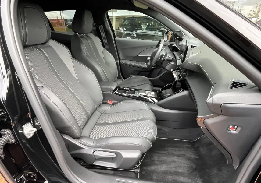 Vue intérieure côté conducteur du Peugeot 2008 GT 2024 noir, sièges en cuir et tissu avec console centrale moderne.