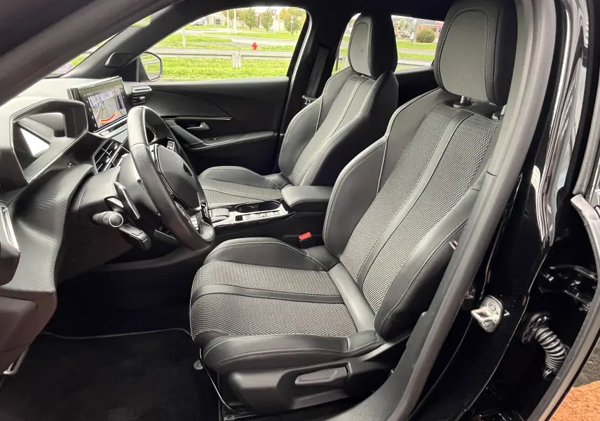 Vue intérieure côté conducteur du Peugeot 2008 noir 2024, mettant en valeur les sièges sport et le tableau de bord digital.