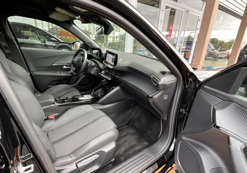 Vue intérieure côté conducteur du Peugeot 2008 noir 2024, mettant en valeur les sièges en cuir et le tableau de bord moderne avec écran tactile.