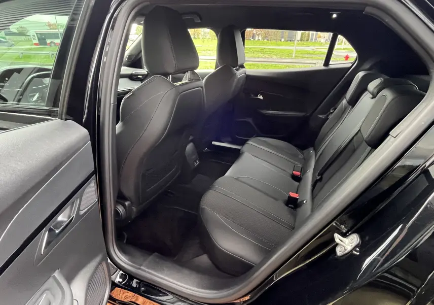 Vue intérieure arrière côté gauche du Peugeot 2008 noir 2024, montrant les sièges arrière en tissu avec surpiqûres claires.