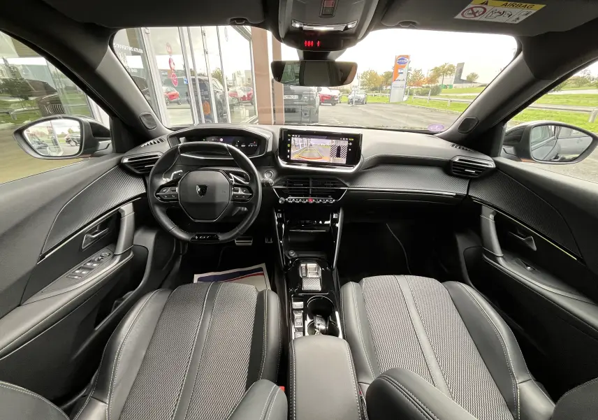 Vue intérieure avant du Peugeot 2008 noir 2024, mettant en valeur le tableau de bord numérique et l'écran central tactile avec caméra de recul.