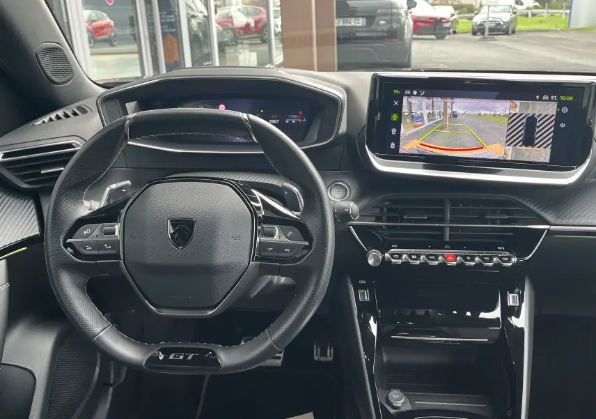 Vue intérieure frontale du tableau de bord du Peugeot 2008 noir 2024, avec volant GT et écran tactile affichant caméra 360°.