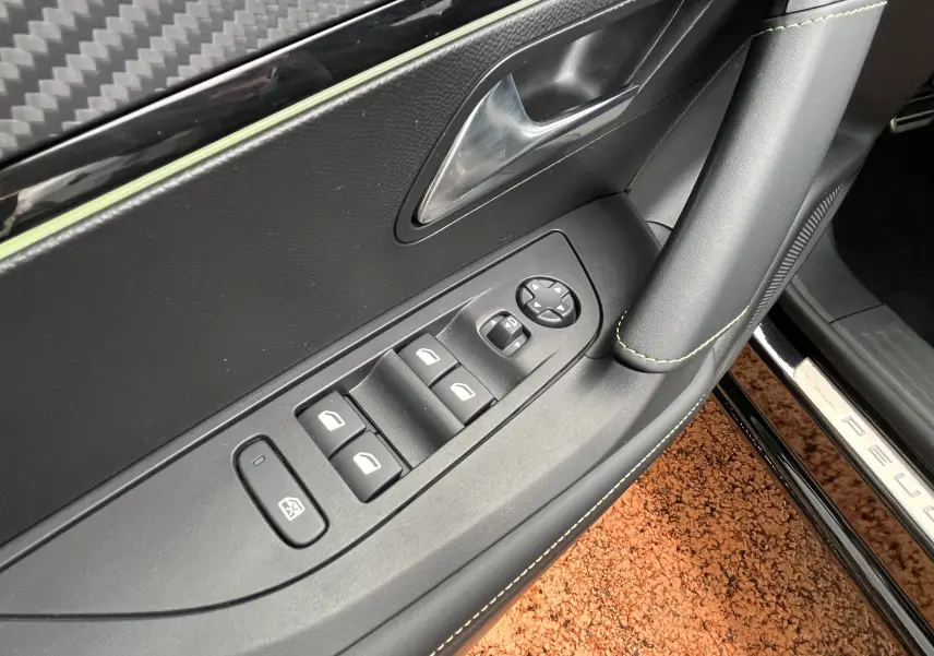 Gros plan sur la commande des vitres côté gauche du Peugeot 2008 noir 2024, avec surpiqûres jaunes et seuil de porte visible.