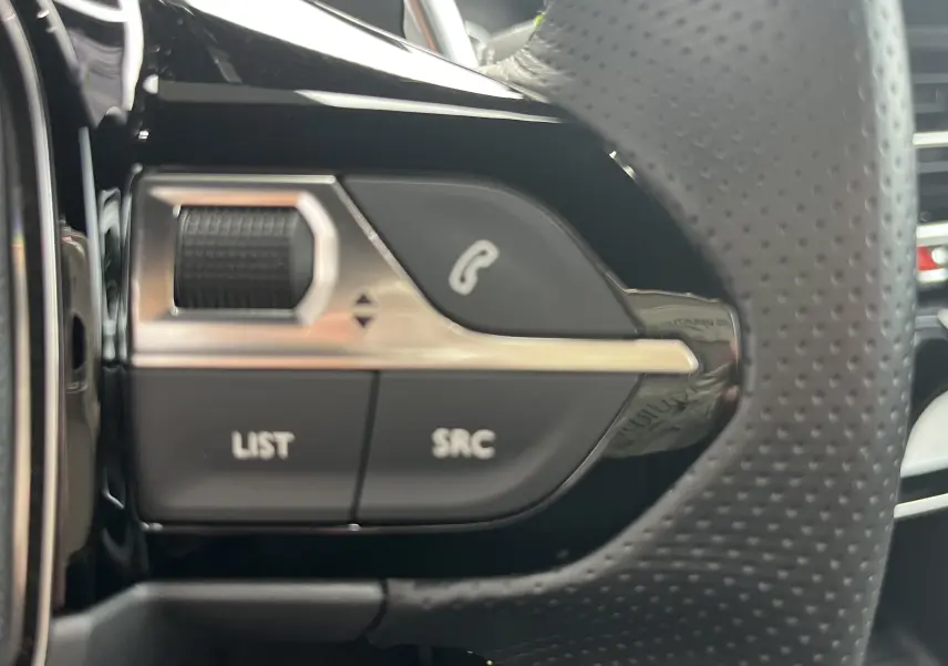 Gros plan sur les commandes multifonctions à gauche du volant perforé du Peugeot 2008 noir, version GT 2024.