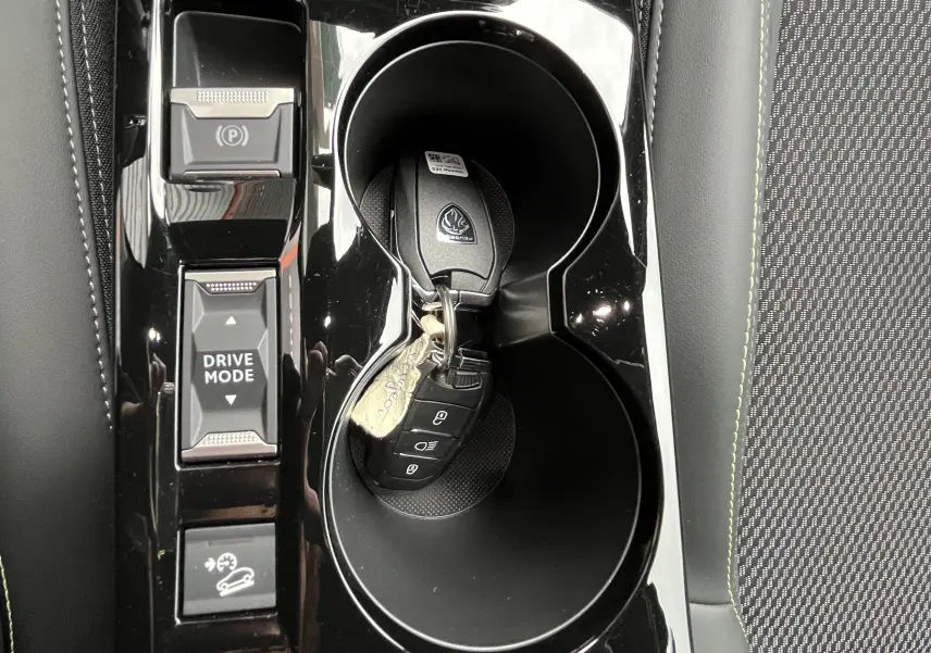 Vue rapprochée de la console centrale noire du Peugeot 2008 avec clés dans les porte-gobelets et boutons Drive Mode et frein à main.