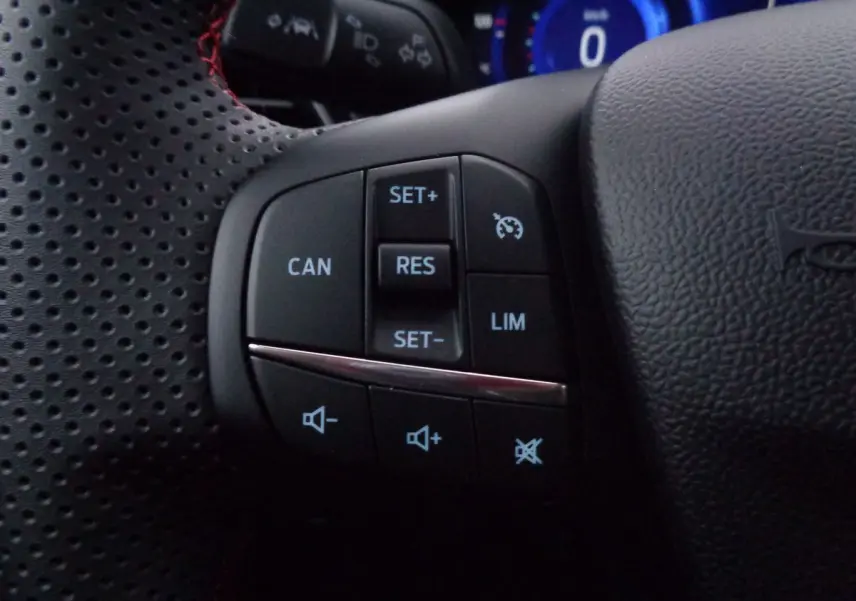 Gros plan sur les commandes de régulateur et volume au volant perforé noir du Ford Puma 1.0 EcoBoost MHEV 2022.