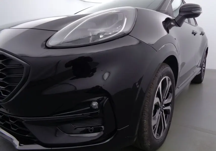 Gros plan sur l'avant droit noir agate métallisé du Ford Puma 1.0 EcoBoost MHEV 155ch ST-Line avec phares LED et jantes bi-ton.