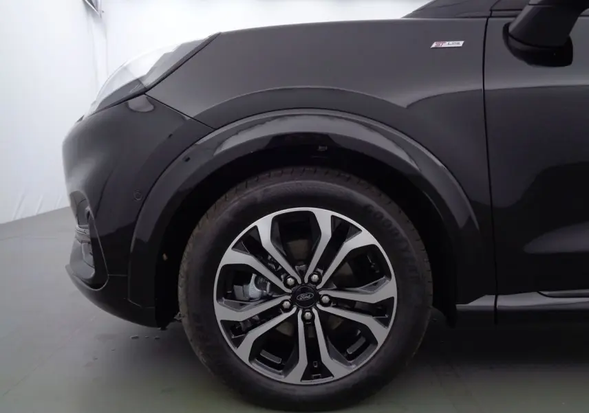 Gros plan sur la roue avant gauche et l'aile noire agate métal du Ford Puma 1.0 EcoBoost MHEV 155ch ST-Line.
