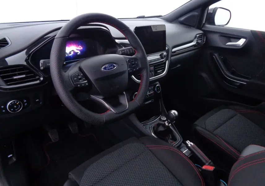 Intérieur de la Ford Puma 1.0 EcoBoost MHEV 2022, vue côté conducteur, sièges noirs avec surpiqûres rouges et volant multifonction.