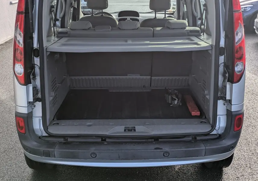 Vue arrière ouverte du Renault Kangoo II bleu ciel, montrant le coffre spacieux et la banquette arrière rabattue.