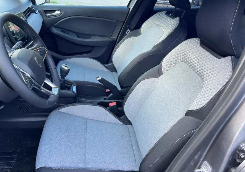 Intérieur de la Renault Clio DCI 100 Evolution Camera 2025, sièges gris clair avec surpiqûres et volant noir visible côté conducteur.