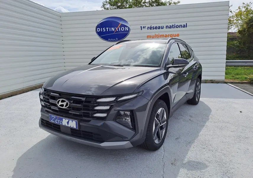 Hyundai Tucson IV Ph.2 Style gris Ecotronic en 3/4 avant droit avec calandre noire et jantes bi-ton.