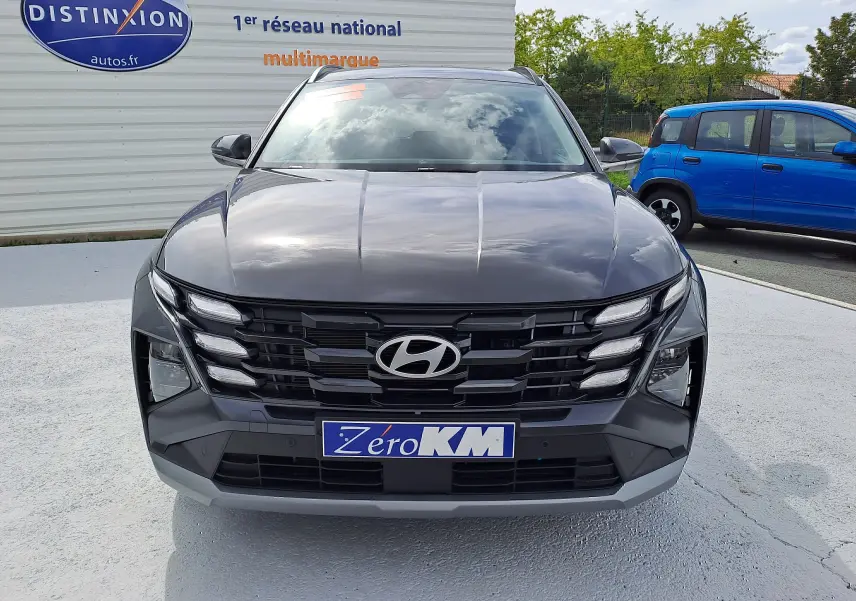 Vue frontale d'un Hyundai Tucson 2025 gris Ecotronic avec calandre noire et plaque "Zéro KM" visible.