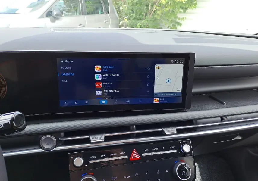 Tableau de bord noir du Hyundai Tucson 2025 avec écran tactile affichant la radio DAB et commandes climatisation.