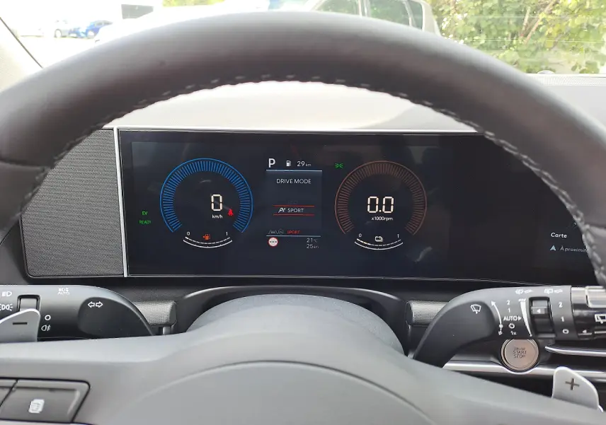 Vue rapprochée du tableau de bord numérique du Hyundai Tucson gris, avec affichage du mode de conduite et volant en premier plan.