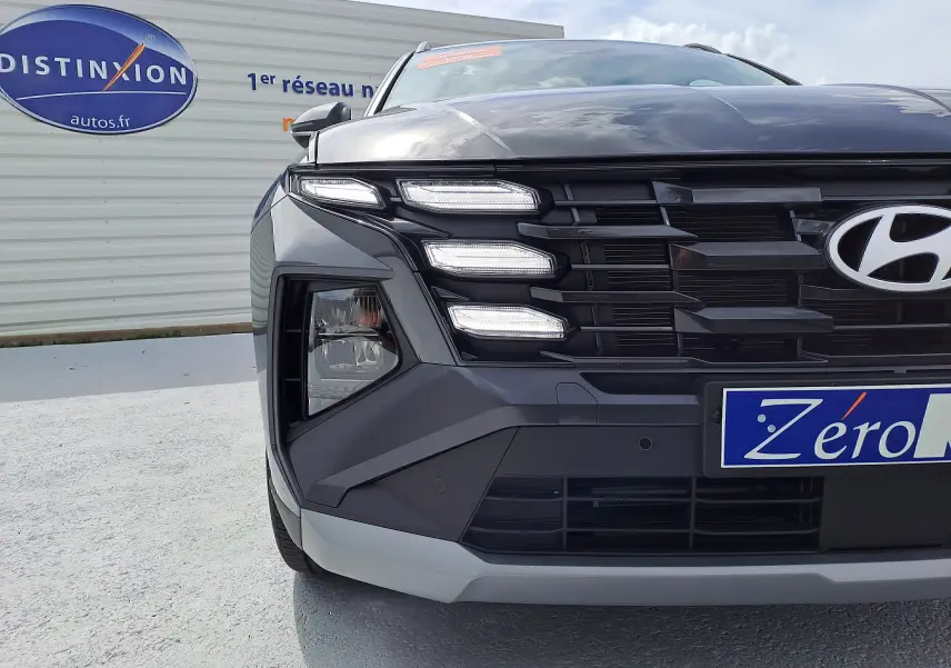 Gros plan sur l'avant droit du Hyundai Tucson 2025 gris Ecotronic, mettant en valeur ses feux LED distinctifs et la calandre noire.