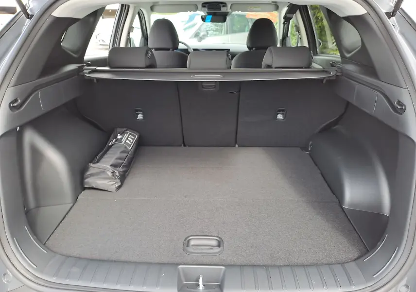 Coffre ouvert d'un Hyundai Tucson 2025 gris Ecotronic, montrant l'espace de chargement avec cache-bagages et siège arrière noir.