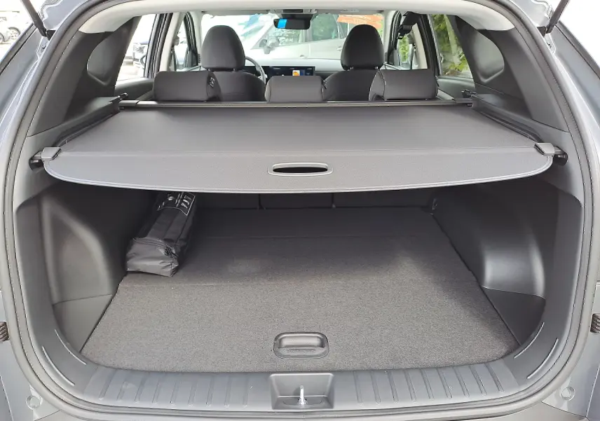 Coffre ouvert d'un Hyundai Tucson 2025 gris Ecotronic, avec cache-bagages déployé et intérieur noir visible.