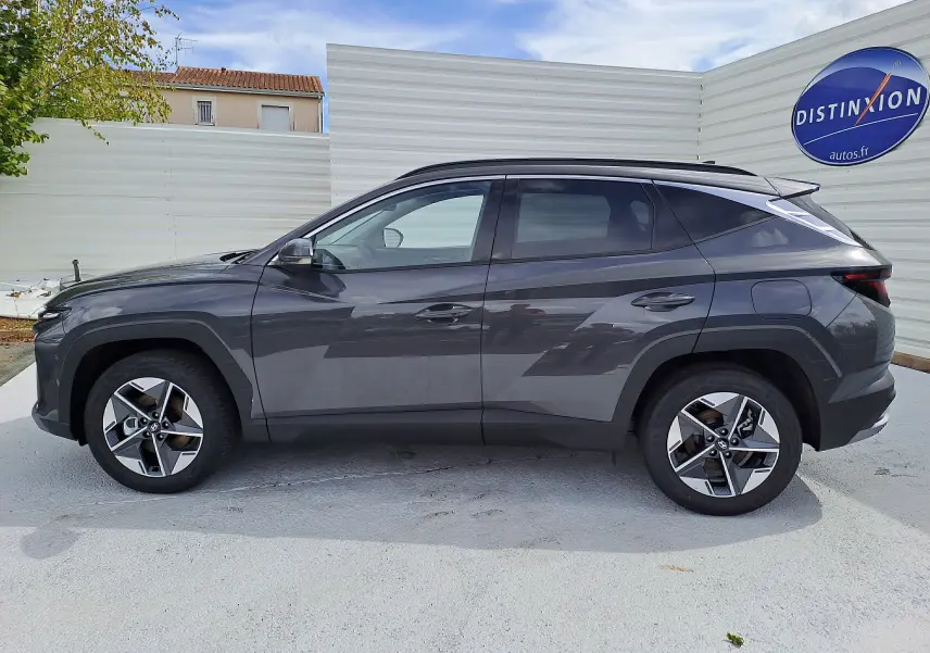 Profil côté gauche du Hyundai Tucson 2025 hybride en gris Ecotronic, avec jantes alliage et toit noir contrasté.