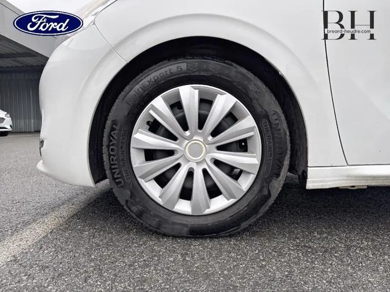 Gros plan sur la roue avant gauche d'une Peugeot 208 blanche Banquise avec jante en alliage et pneu dégonflé.