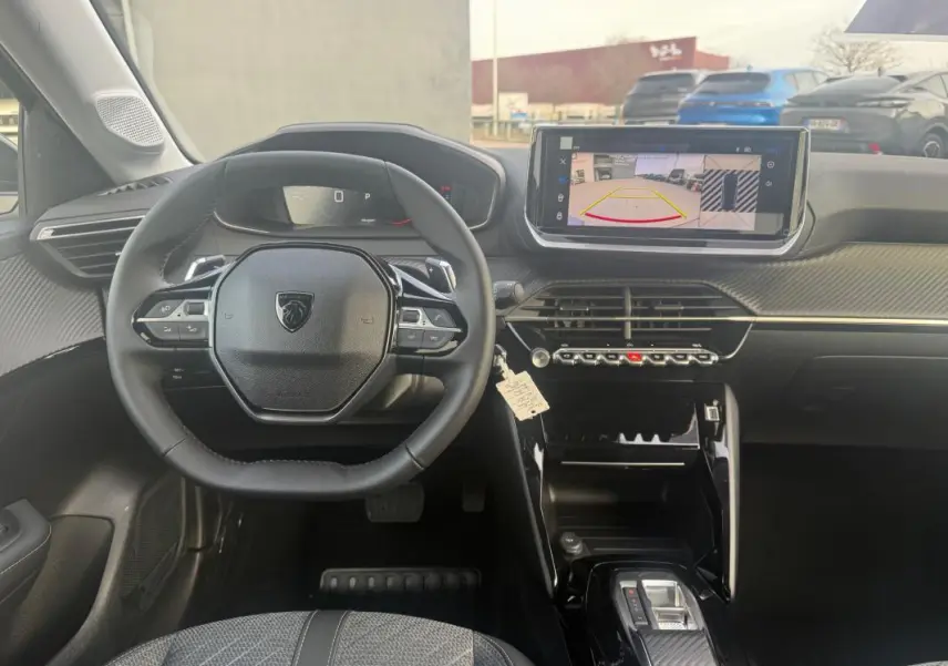 Vue intérieure frontale du poste de conduite de la Peugeot 208 Hybrid 110 gris, avec écran tactile et volant multifonction.