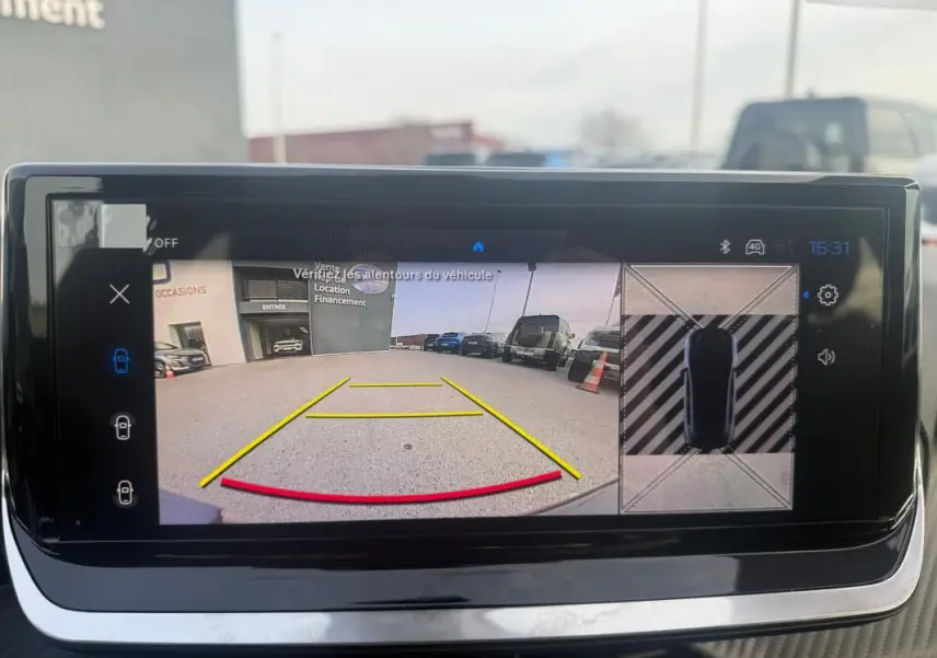 Écran tactile montrant la caméra de recul et vue aérienne du parking, intérieur d'une Peugeot 208 gris 3/4 arrière.