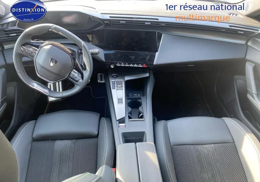 Vue intérieure plongeante du poste de conduite noir du Peugeot 408 Hybrid 145 GT avec volant cuir et écran tactile central.