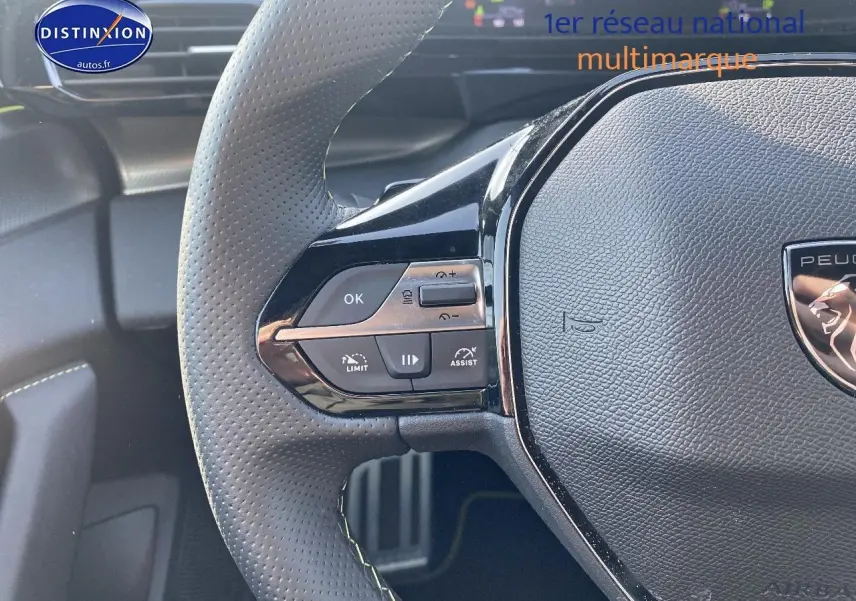 Gros plan sur le volant cuir noir perforé de la Peugeot 408 Hybrid 145 GT avec commandes intégrées côté gauche.