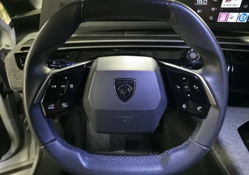 Volant compact cuir noir avec logo Peugeot au centre, commandes intégrées, vue rapprochée de l'intérieur du Peugeot 3008 2025.