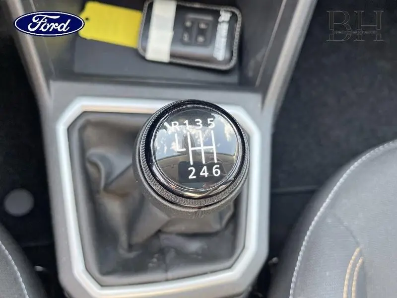 Gros plan sur le levier de vitesses manuel noir de la Dacia Sandero blanche, avec clé de contact visible en arrière-plan.